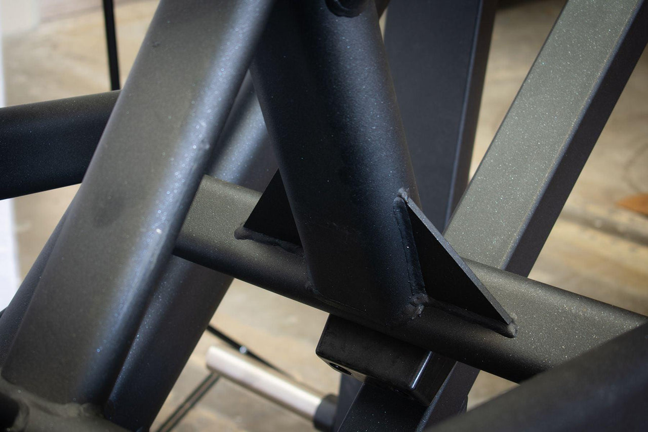 Close-up of the black metal frame and welds of the leg press machine.