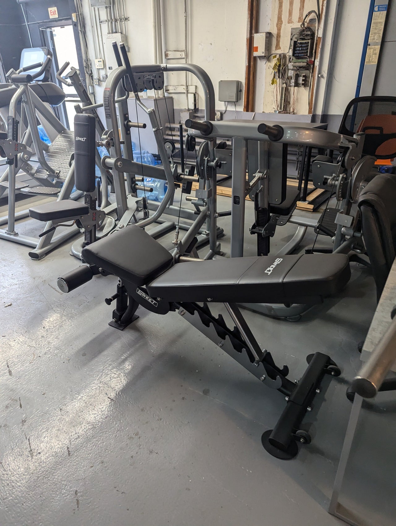 Black and gray adjustable weight bench in a gym setting.