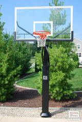 Adjustable basketball hoop with a clear glass backboard and orange rim, set up outdoors.