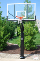 Adjustable basketball hoop with clear backboard and orange rim, set up outdoors on a paved area.