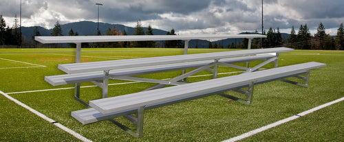 Aluminum 3-row bleacher on a green sports field with mountains and trees in the background.