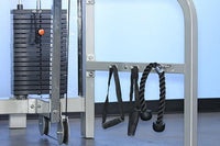 Thumbnail for Close-up of a gym machine with a weight stack, pulleys, and two black cable attachments hanging on a bar.