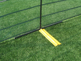 Black fence post on a T-shaped base held down by a yellow weight bag, with black mesh fencing on turf
