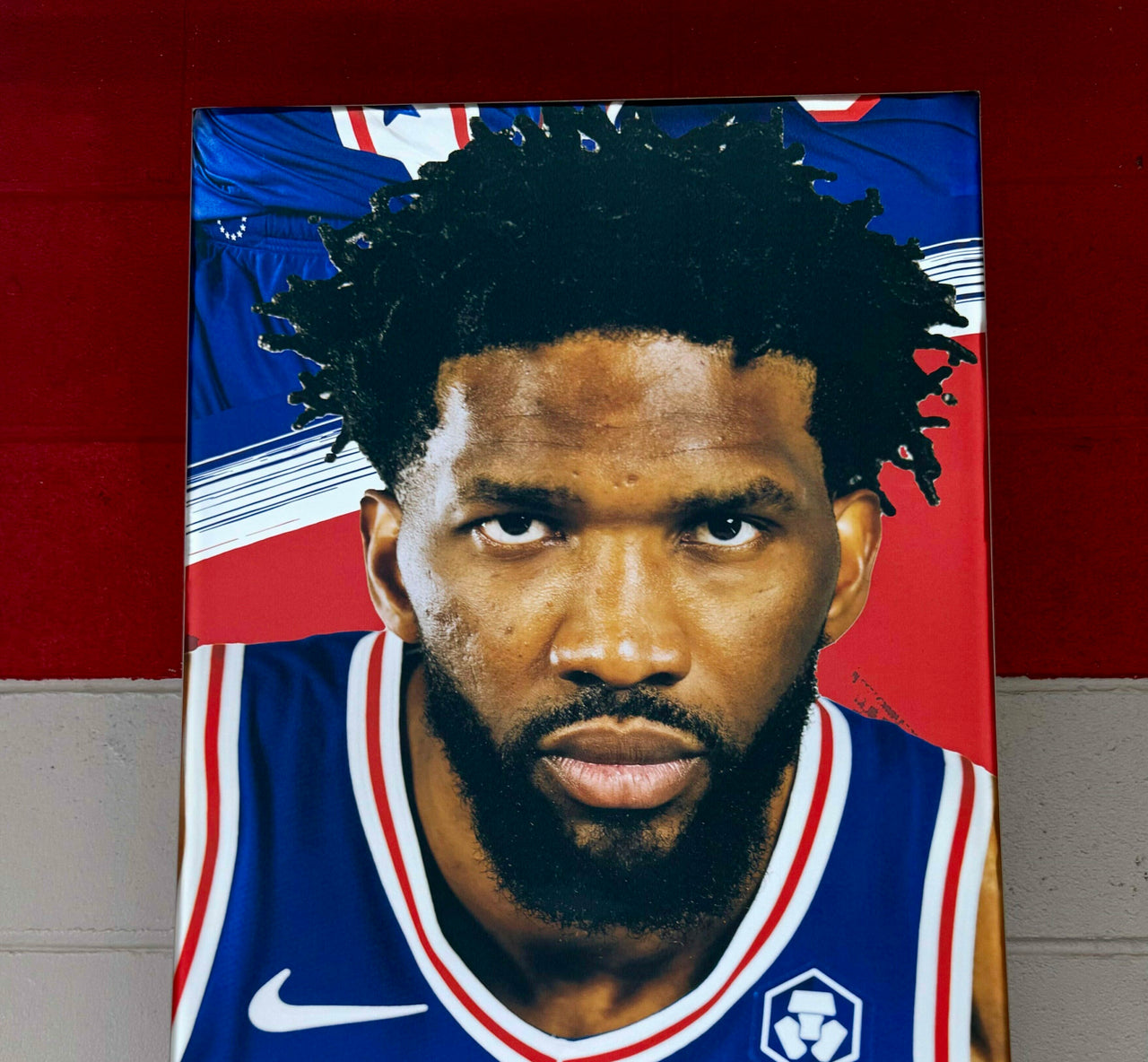 Close-up of a silicone edge graphic portrait of a basketball player in a blue jersey hung on a red and white wall