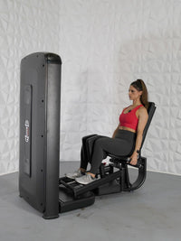 Thumbnail for Woman in red top and black leggings using a black inner and outer thigh exercise machine.