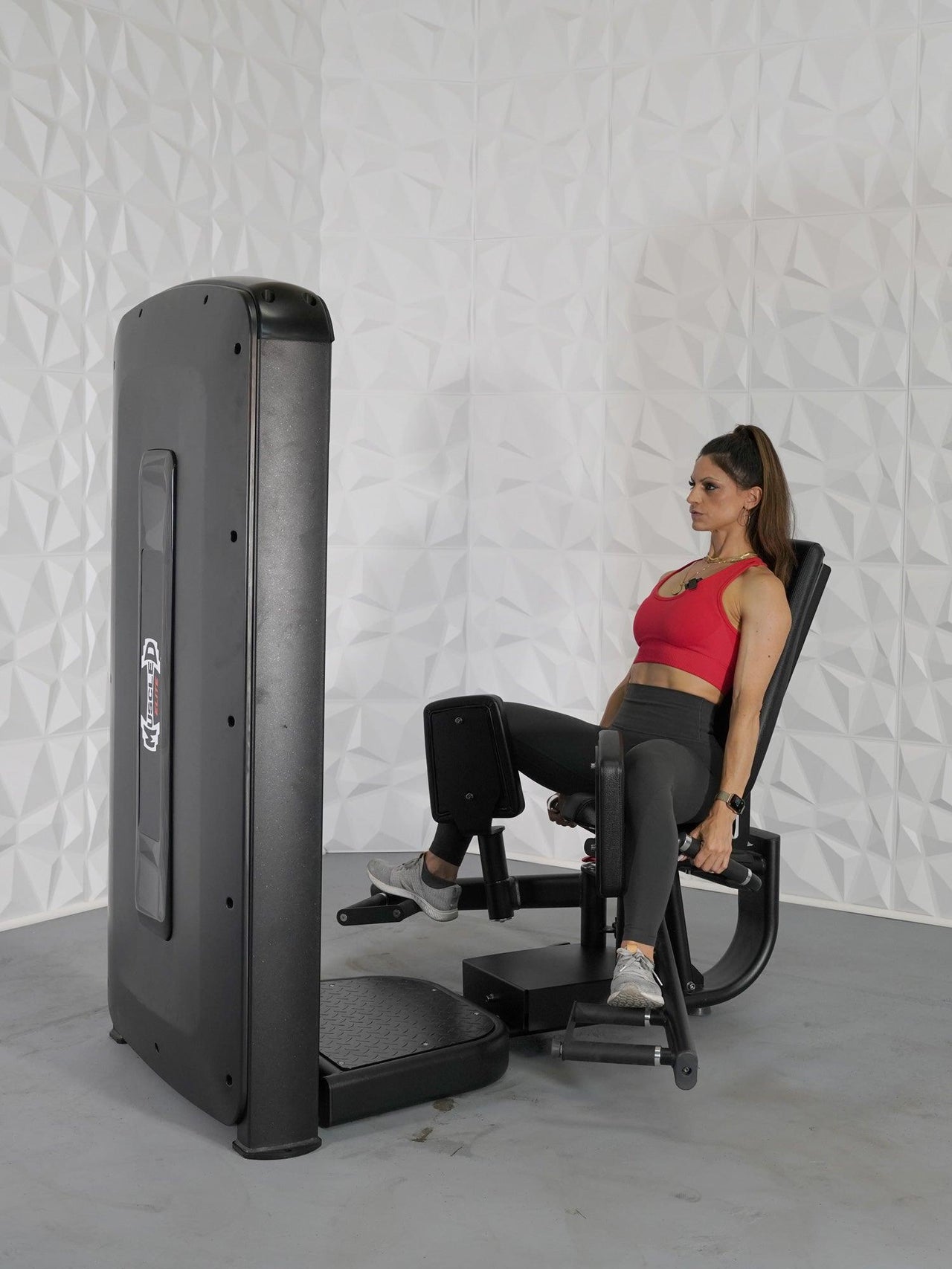 Woman in red top using a black thigh adduction/abduction machine.
