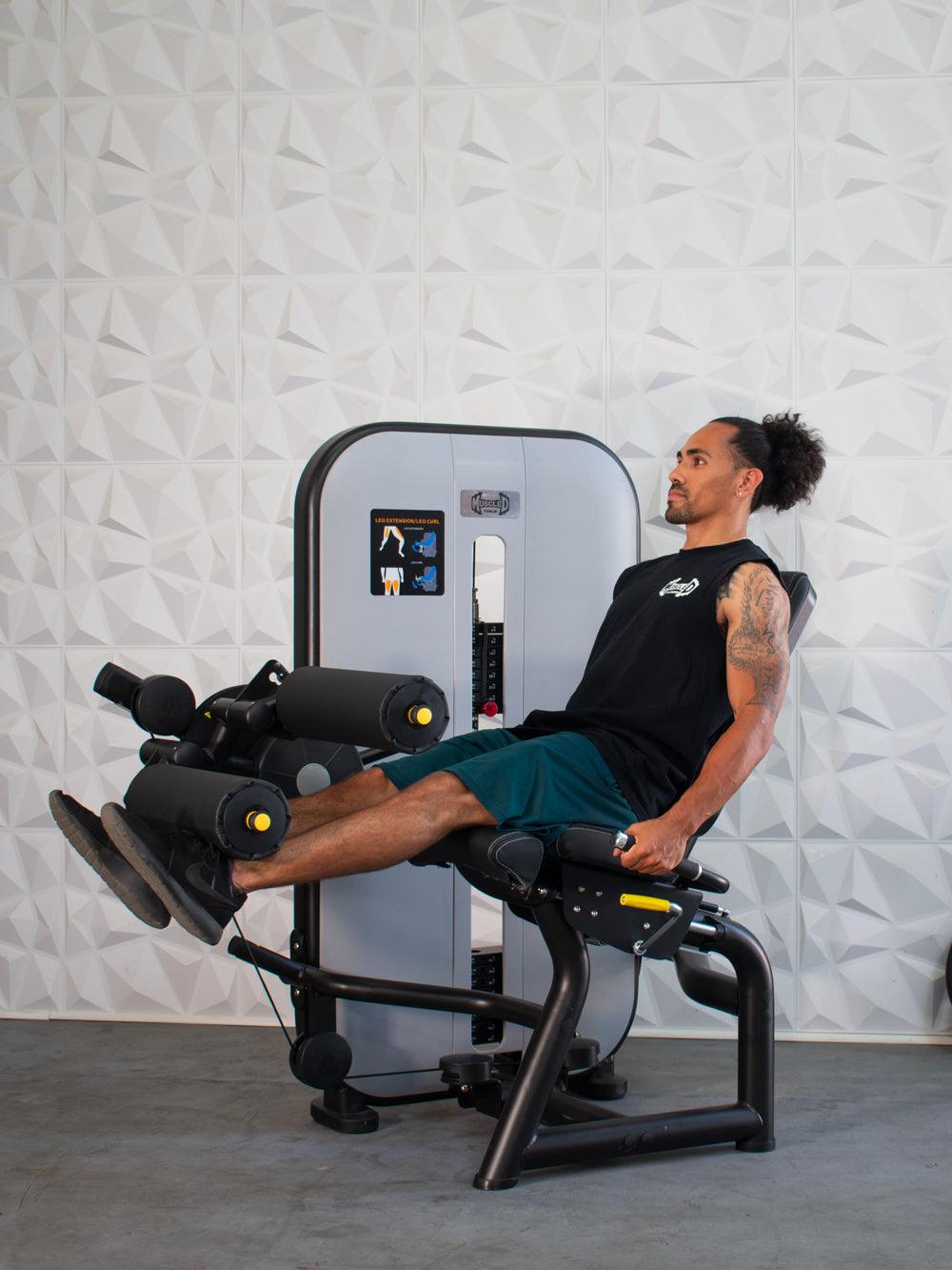 Man using a leg extension/curl machine, extending his legs forward.