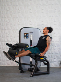 Thumbnail for Man using a leg extension/curl machine, extending his legs forward.