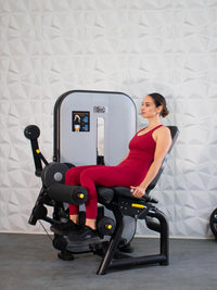 Thumbnail for Woman in red using a leg extension/curl machine, performing a leg extension.