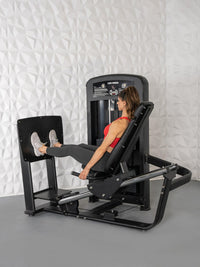 Thumbnail for Woman using a black leg press machine with a pin-selectorized weight stack.