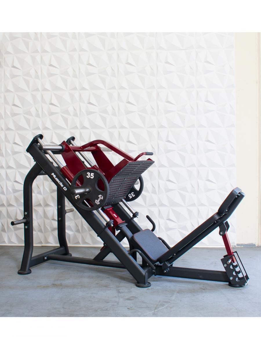 Red and black linear bearing leg press machine with 35lb weight plates, against a white textured wall.