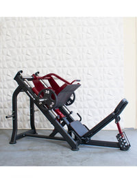 Thumbnail for Red and black linear bearing leg press machine with 35lb weight plates, against a white textured wall.