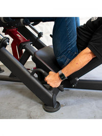 Thumbnail for Person in jeans and black shirt using a leg press machine, holding onto handles.