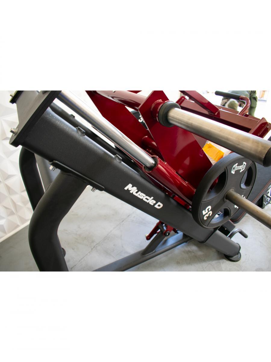 Close-up of a red and black leg press machine with "Muscle D" logo and a 35lb weight plate.
