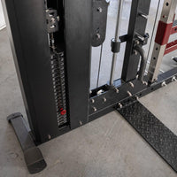 Thumbnail for Close-up of a weight stack on a black fitness machine with a red weight pin and diamond plate footrest.