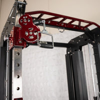 Thumbnail for Close-up of a red pulley system and black handle on a silver and black fitness machine.