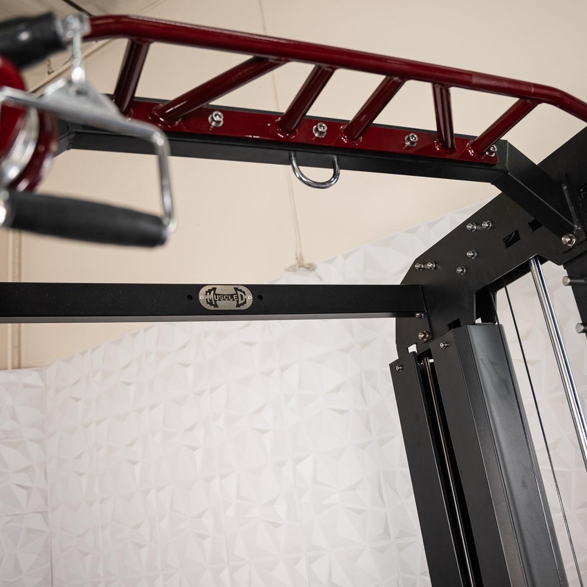 Close-up of a red monkey bar attachment and black frame of a fitness machine with a Muscle D Fitness logo.