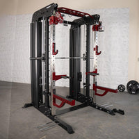Thumbnail for Black and red multi-functional fitness machine with a barbell, cables, and weight plates on the floor.