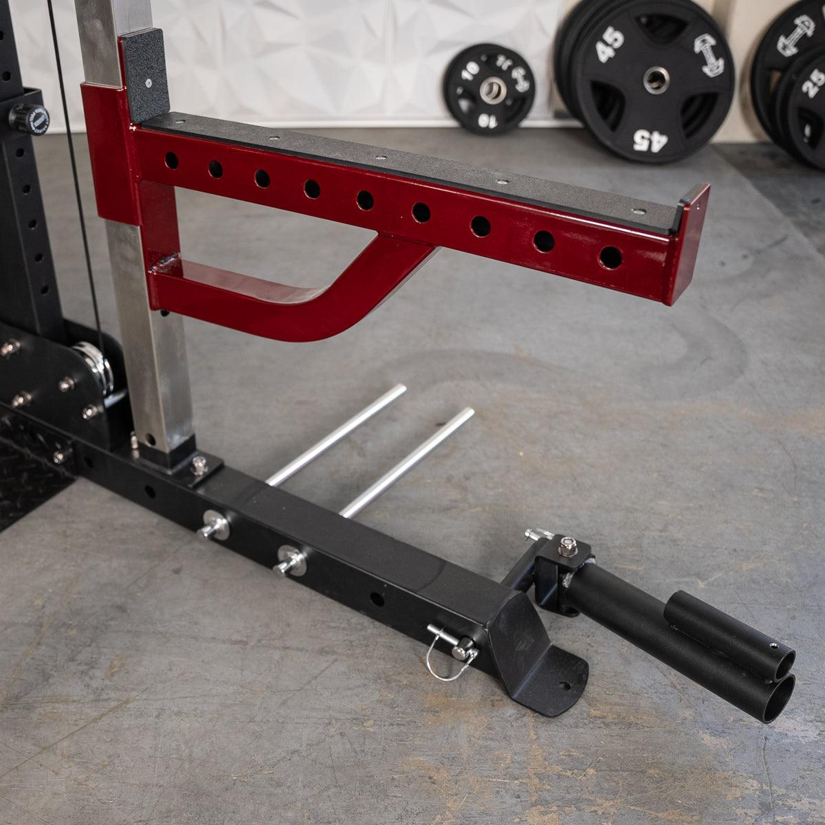 Red and black fitness equipment with weight plate storage, a spotter arm, and a landmine attachment.