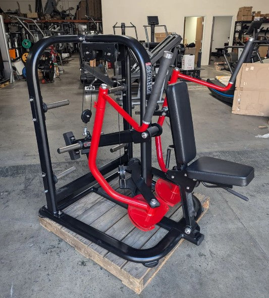 Black and red chest fly machine with a padded seat and handles, on a wooden pallet.