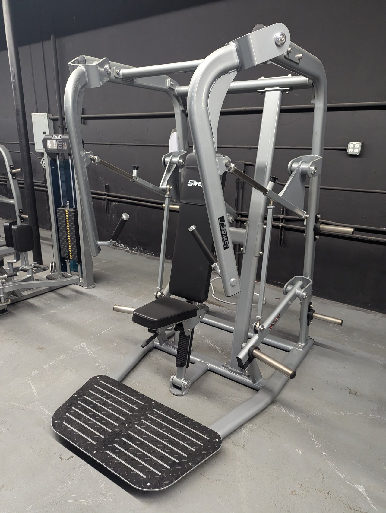 Black and silver chest press machine with a padded seat and foot platform.