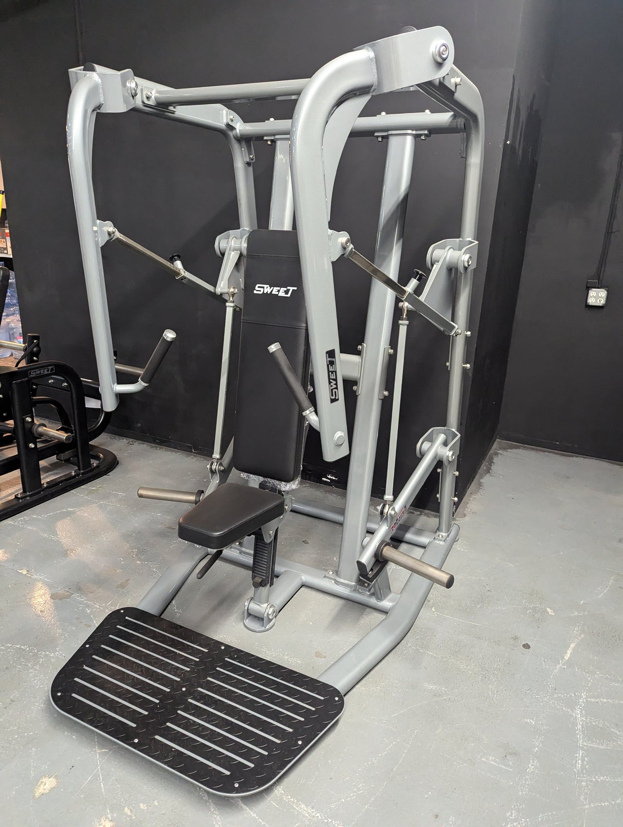 Sweet Chest Press machine in black and silver with a black padded seat and foot platform.