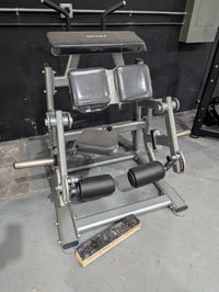 Thumbnail for Silver kneeling leg curl machine with black pads and rollers in a gym setting.