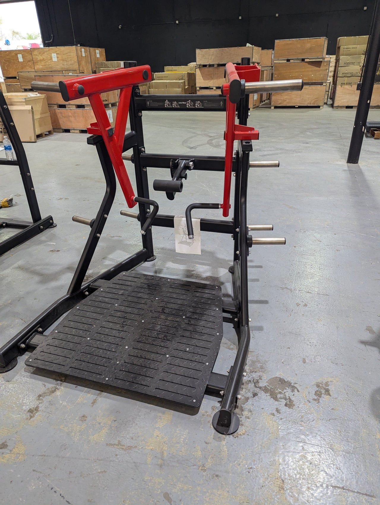 Black and red independent training machine with a textured footplate and weight plate holders.
