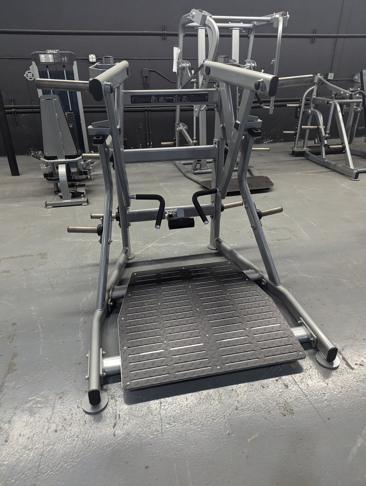 Silver independent training machine with a black textured footplate and handles in a gym.