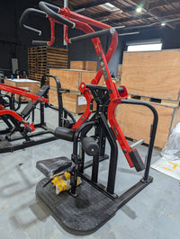 Thumbnail for Red and black rotary lat pull-down machine with padded seat and handles in a warehouse setting.
