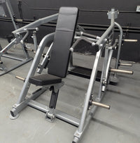 Thumbnail for Silver plate-loaded shoulder press machine with black padded seat and backrest in a gym.