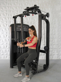Thumbnail for Woman in red top and gray leggings using a black pec deck/rear delt machine.