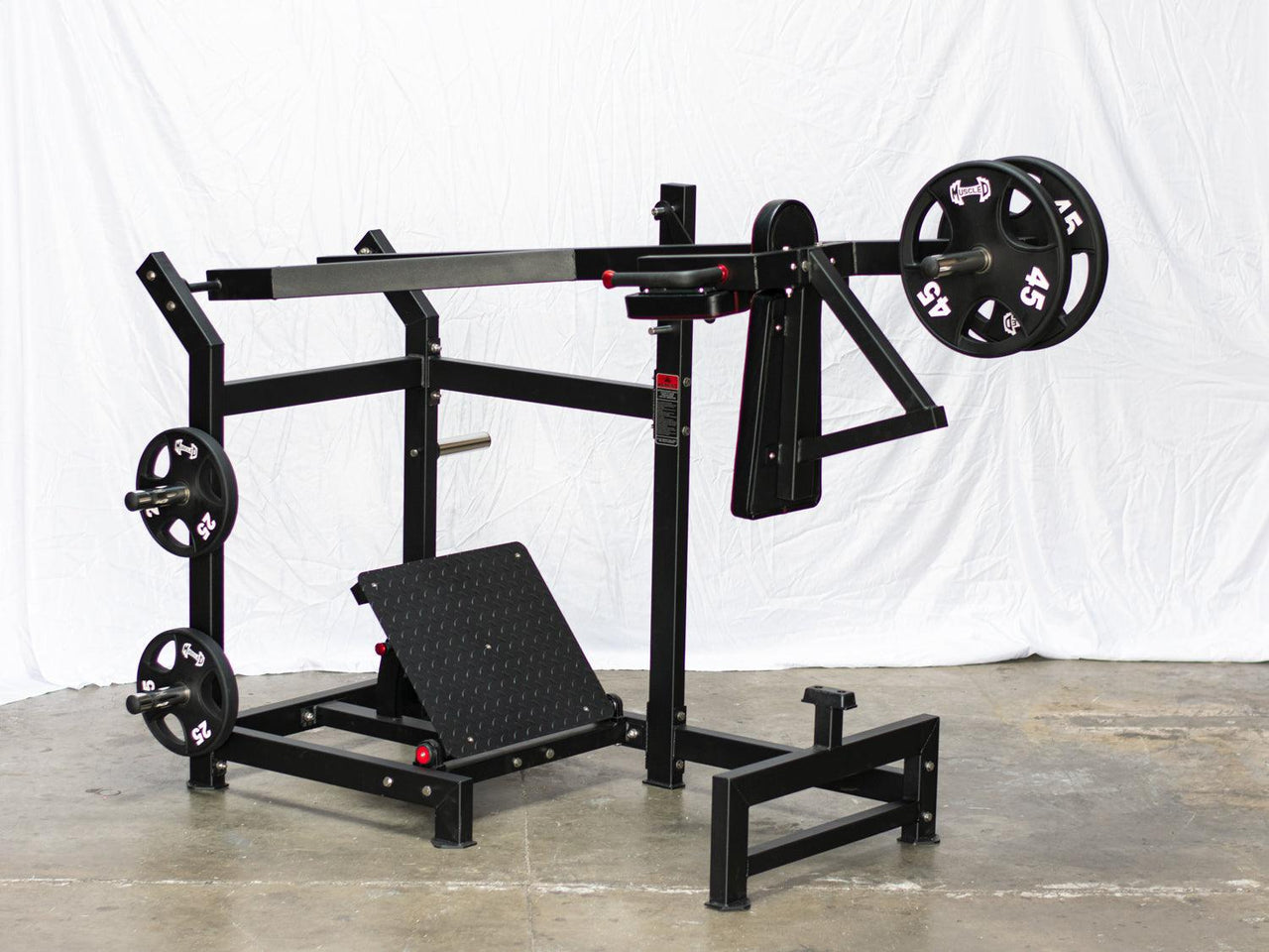 Black plate-loaded pendulum squat machine with weight storage pegs and an adjustable footplate.