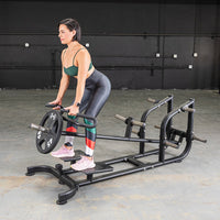 Thumbnail for Woman performing T-bar rows on a black leverage machine with a 45lb weight plate.