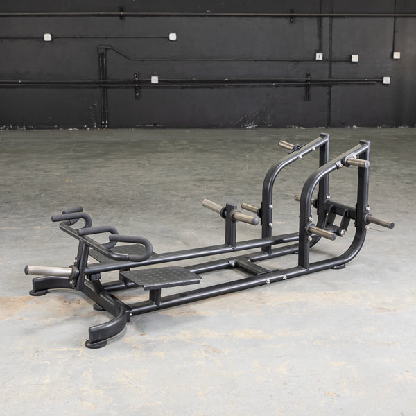 Black T-bar row machine with footplate and multiple grip handles on a concrete floor.