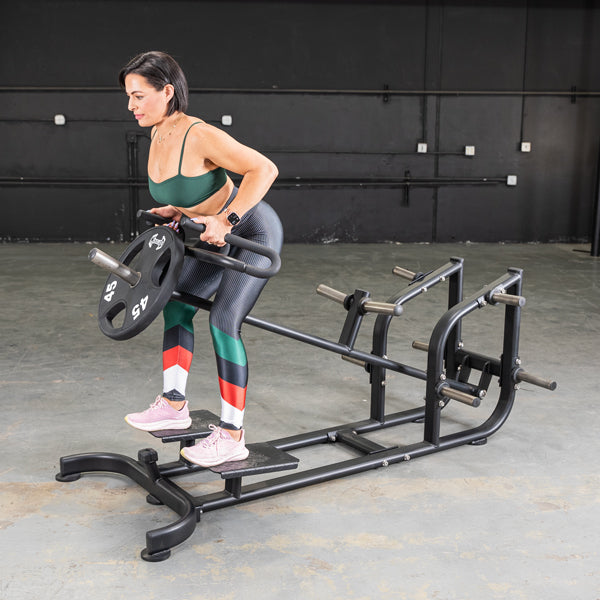 Woman using a black T-bar row machine with a 45lb weight plate in a gym.