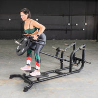 Thumbnail for Woman using a black T-bar row machine with a 45lb weight plate in a gym.