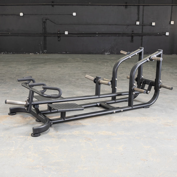 Black T-bar row machine with footplates and multiple grip handles on a concrete floor.