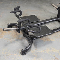 Thumbnail for Black T-bar row machine with two footplates and multiple grip handles on a concrete floor.