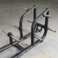 Thumbnail for Black metal T-bar row machine with multiple weight plate holders on a concrete floor.