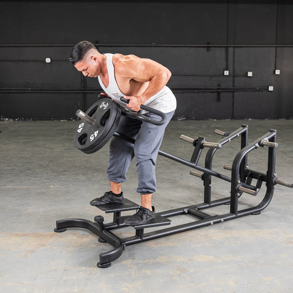 Man using a black T-bar row machine with weight plates in a gym.