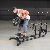 Thumbnail for Man using a black T-bar row machine with weight plates in a gym.