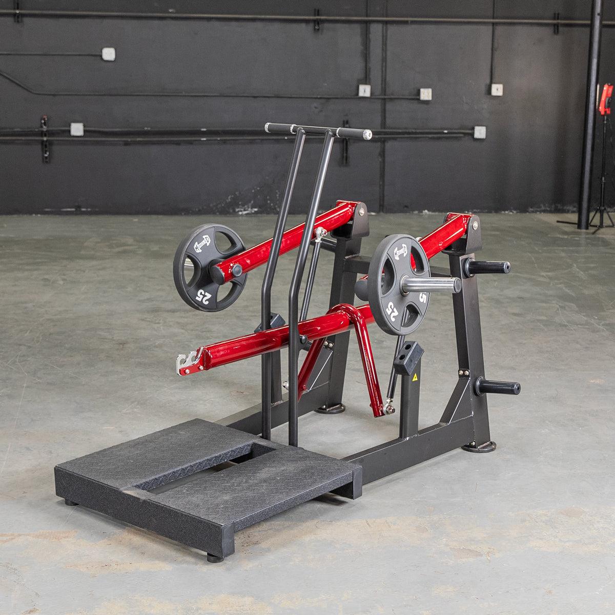 Black and red belt squat machine with weight plates on a concrete floor.