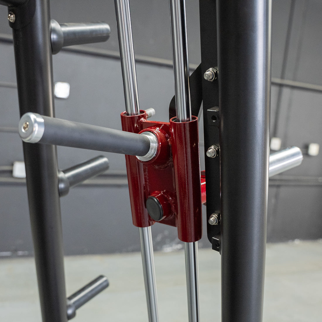 Close-up of a red weight bar attachment with a black grip handle on a fitness machine.