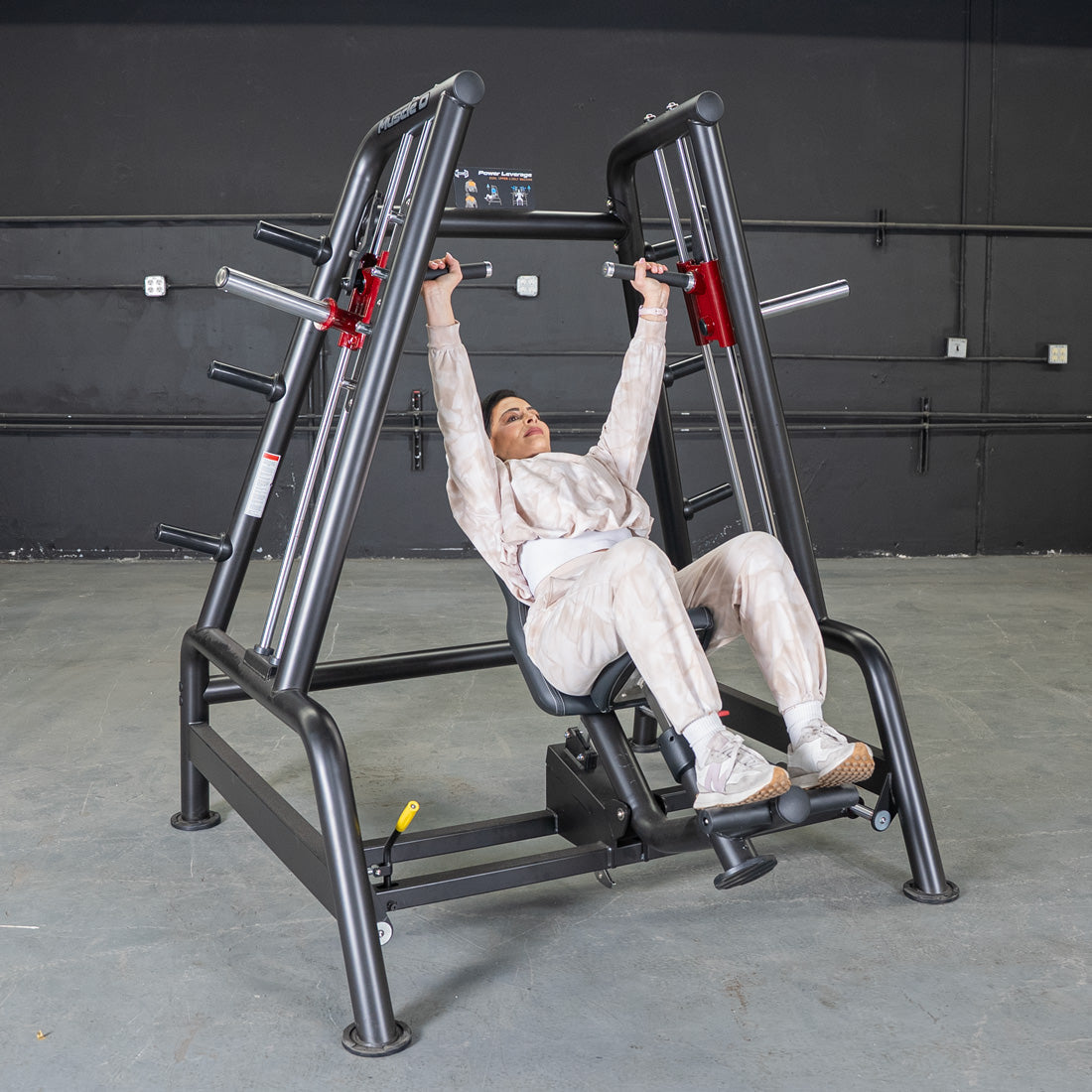 Woman in beige sweats using a black Power Leverage V2 Convergent Bench for an incline shoulder press.