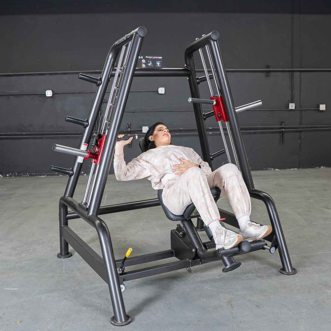 Woman using a black and red Power Leverage V2 Convergent Bench for an incline press.