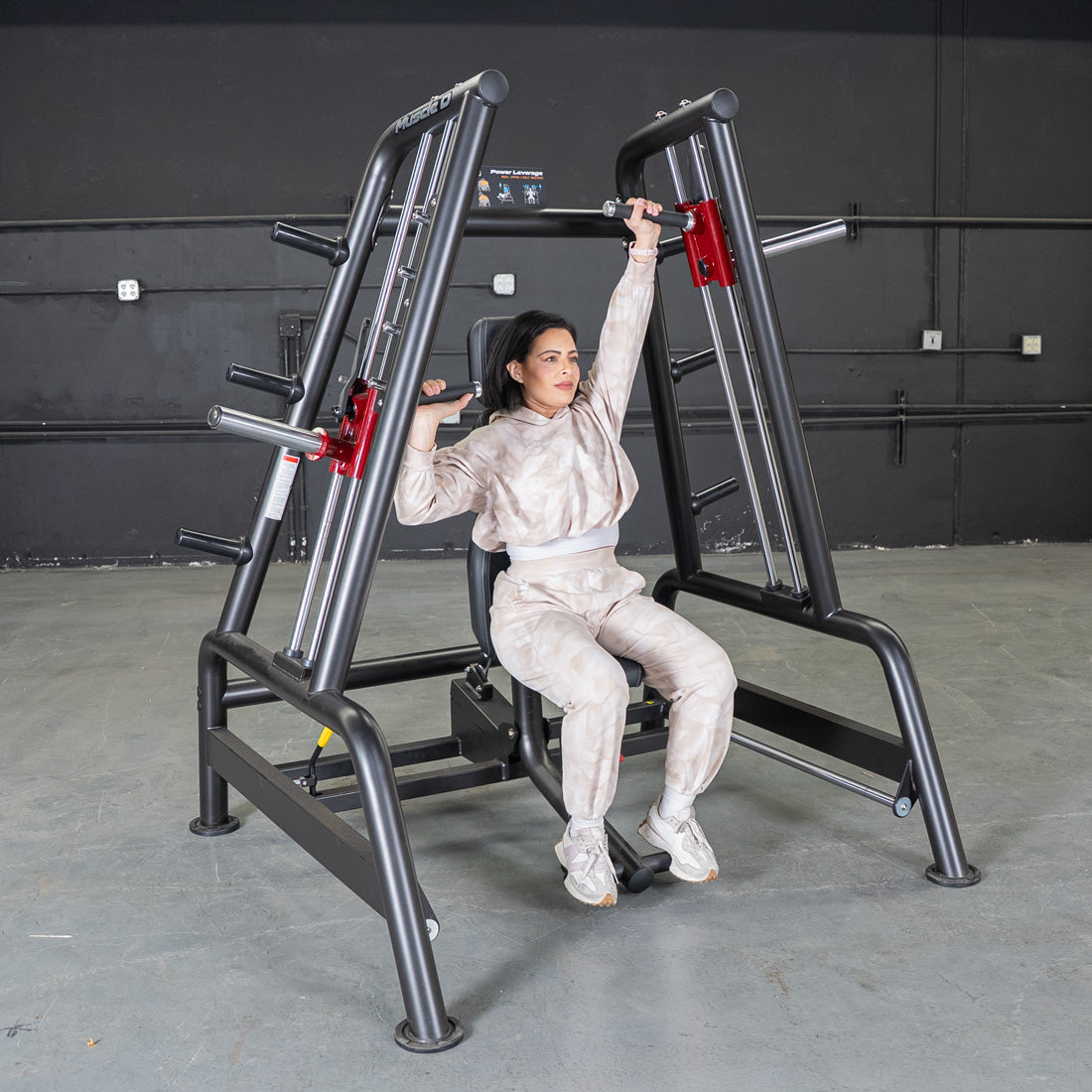 Woman using a Power Leverage V2 Convergent Bench for an incline shoulder press in a gym.