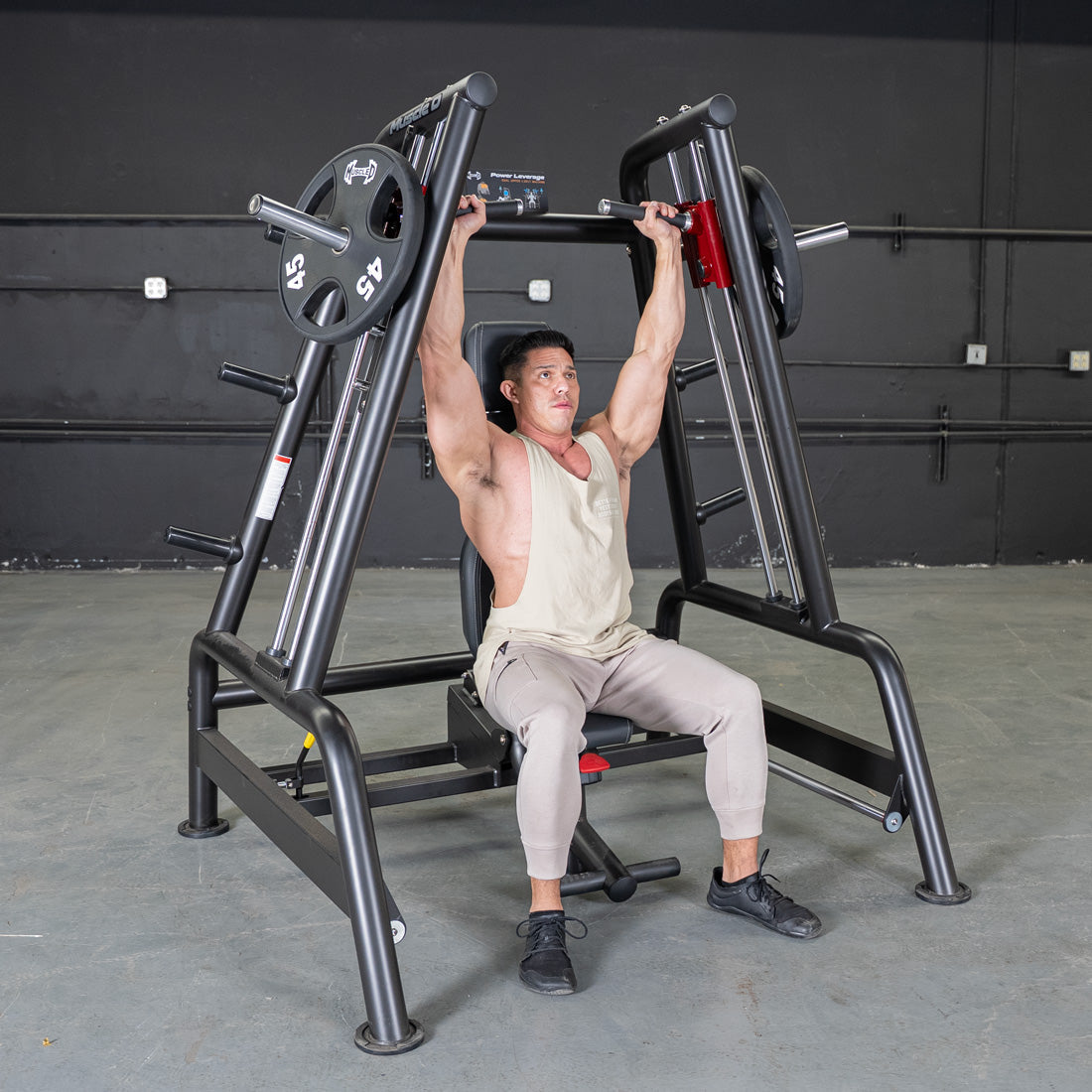 Man using a black Power Leverage V2 Convergent Bench with 45lb plates to do an overhead press.