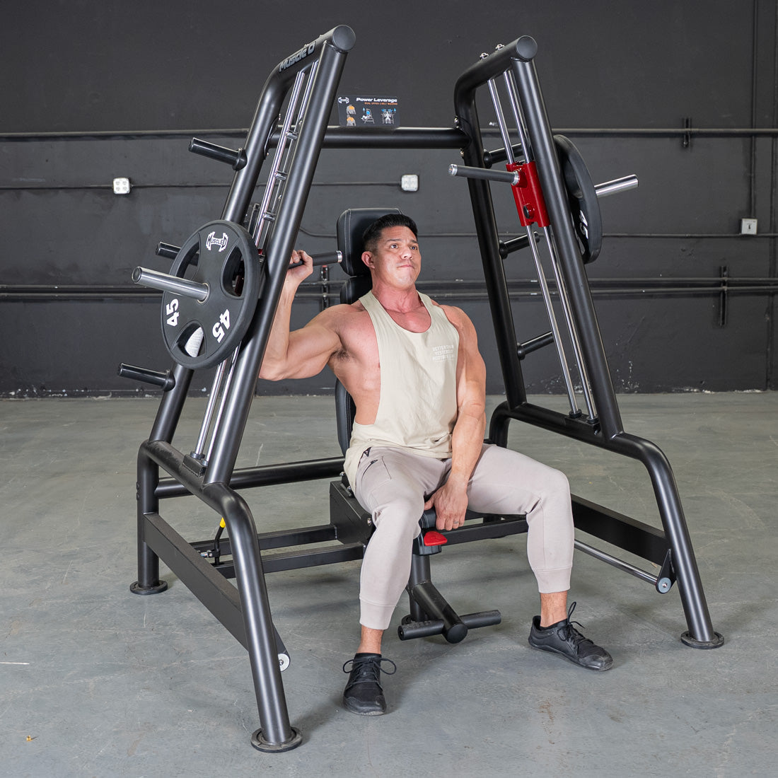 Man using a black Power Leverage V2 Convergent Bench with 45lb weight plates in a gym.
