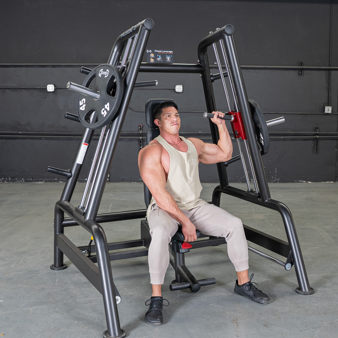 Man using a black and red convergent bench press machine with weight plates in a gym.